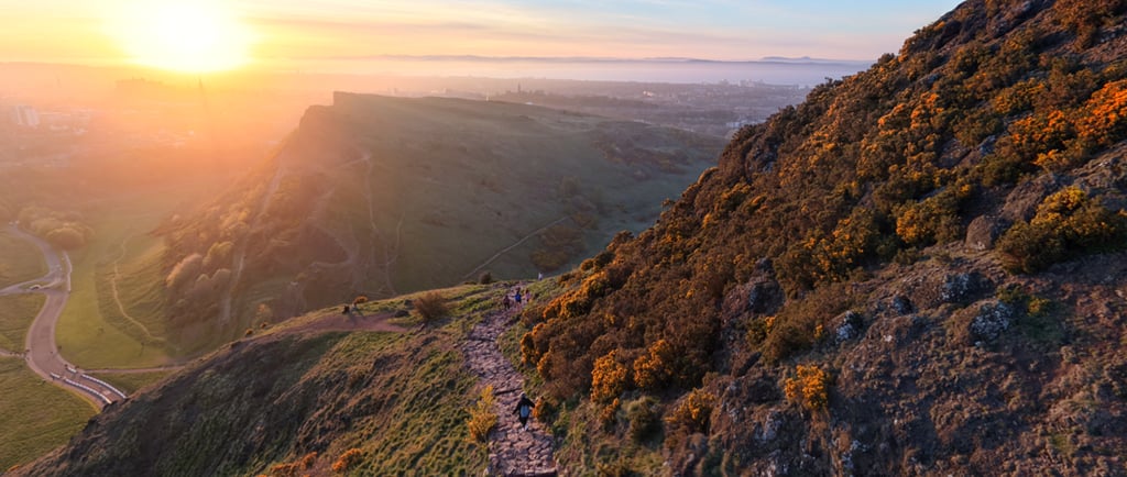 Stone hiking path on Arthur's Seat Edinburgh at sunrise with Salisbury Crags and city beyond