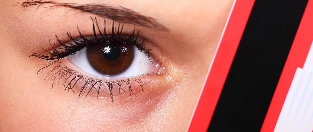 a woman with a red eyeliners and mascara brush