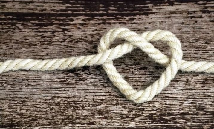 un cœur fait de corde posé sur une planche en bois