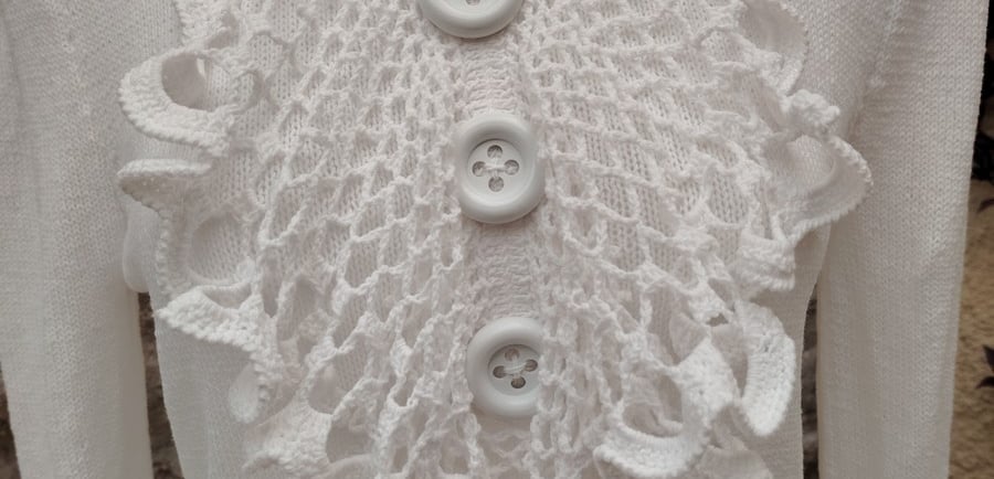 jabot sur un pull blanc deux gros boutons blanc son cousu dessus au milieu