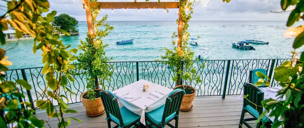 Luxury waterfront balcony dining with a view of boats on turquoise Caribbean waters.
