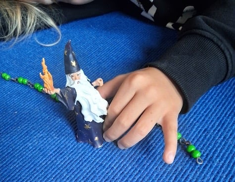 Kinderhand mit Zauberer, der anhand einer Perlenkette die Schritte des 1x1 abgeht.