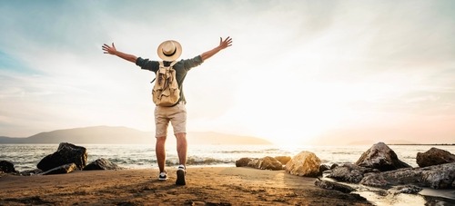 a man standing on a beach with his arms up