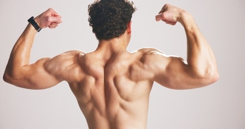 Muscular man flexing his back and arm muscles during a fitness workout bodybuilder pose.