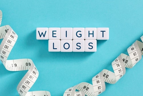 White blocks spelling weight loss surrounded by a white measuring tape on a blue background.