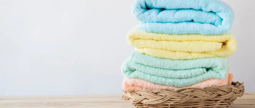 Stack of pastel-colored towels neatly arranged in a wicker basket.