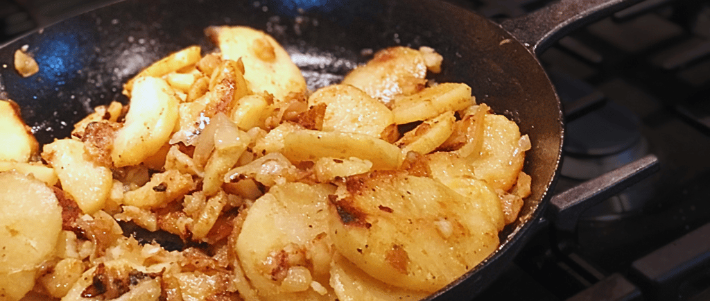 fried skillet postatoes on a stove in  cast iron skillet pan
