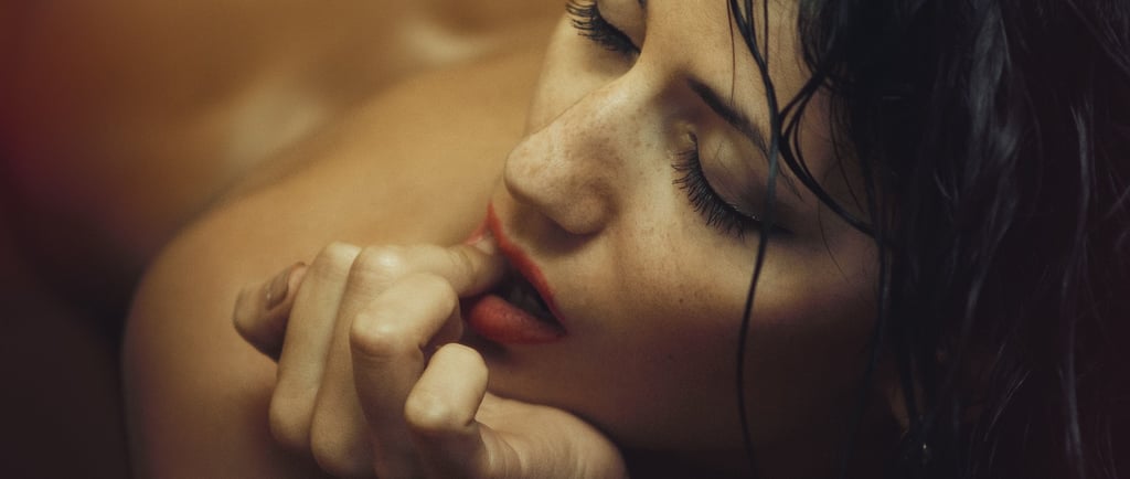 a woman on her front seductively licking a finger