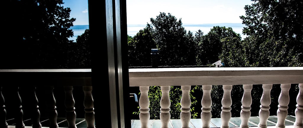 looking through sliding door out over trees with a lake in the background merging with the skyline