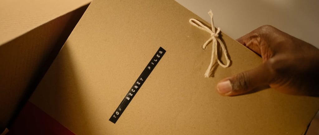 A hand holding a file with the words "top secret" written on it