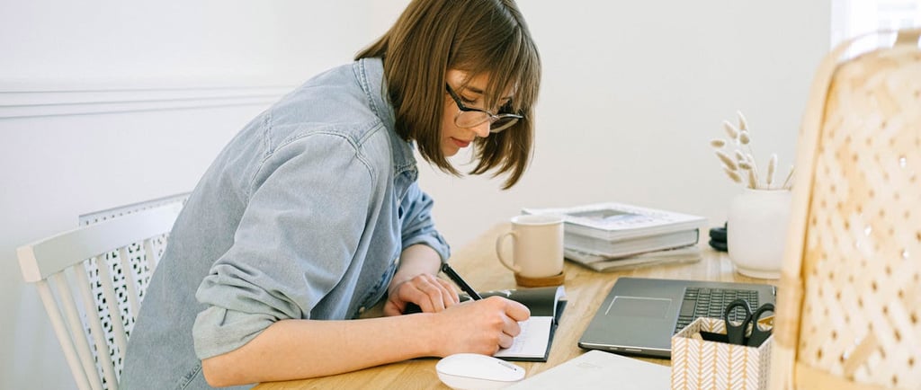 A woman writing on a notepad while sitting in her work station