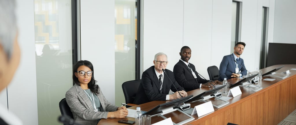 Four people listening attentively to a facilitator during a stakeholder meeting in an office