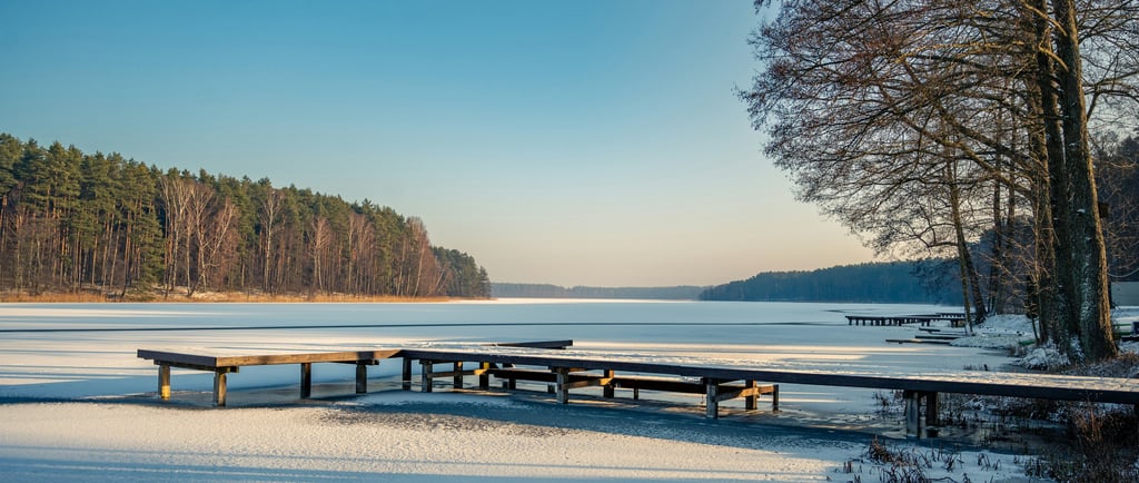 Springtime lake in Canada with partial snow and calm shoreline water.