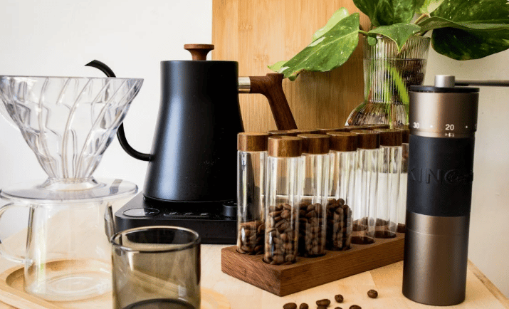 Itens de preparo de café em bancada de madeira com plantas decorativas ao fundo.