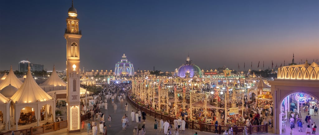 Dubai Global Village at night with colorful lights, cultural pavilions, and crowds of visitors enjoying the festival atmosphe