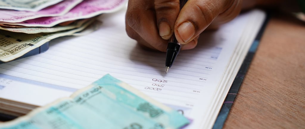 a person holding a pen and writing on a notebook
