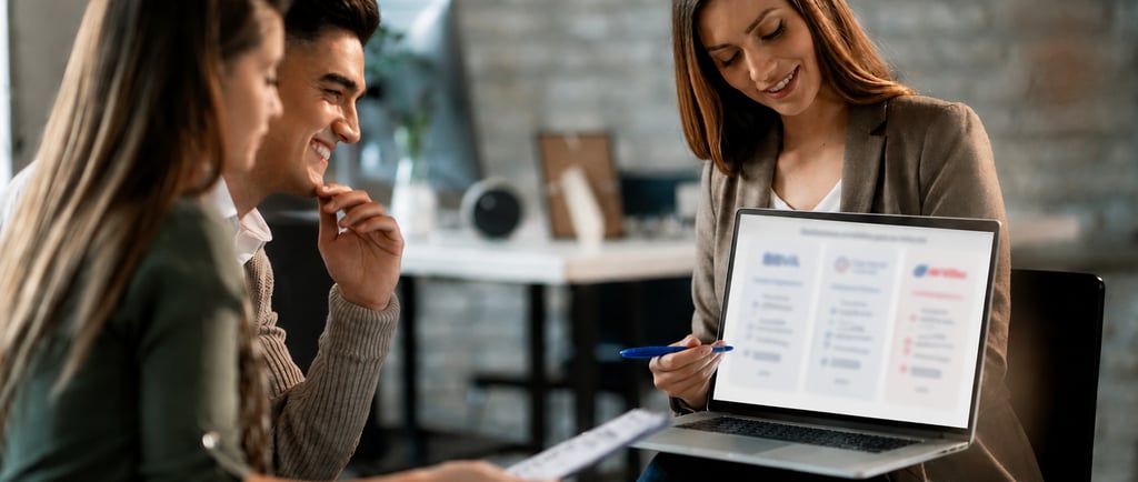 A financial advisor showing a digital business presentation on a laptop to a young couple in a modern office.