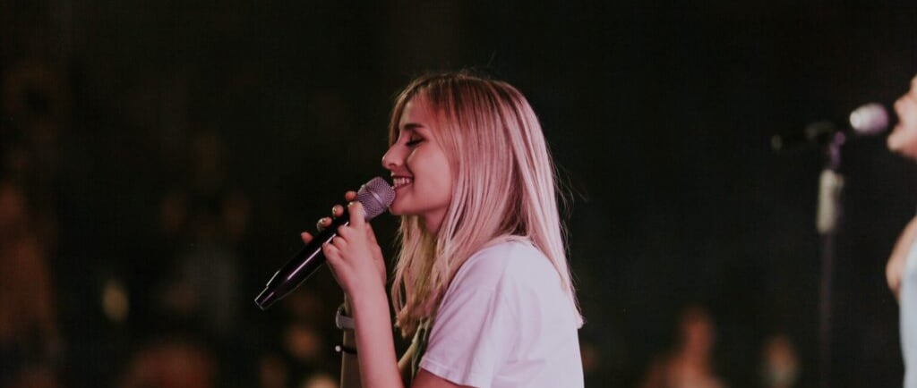 a woman singing into a microphone while holding a microphone