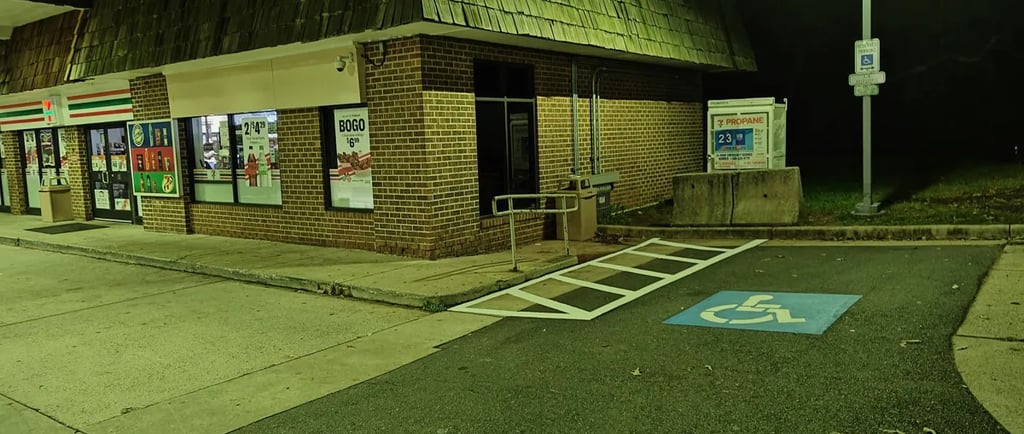 Accessible parking spot with blue ADA symbol and hatched access zone at night.