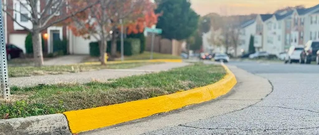 Fresh yellow curb paint in a residential community, highlighting improved visibility and fire lane