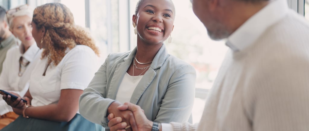 A smiling professional businesswoman shaking hands with a colleague during a networking event or meeting.