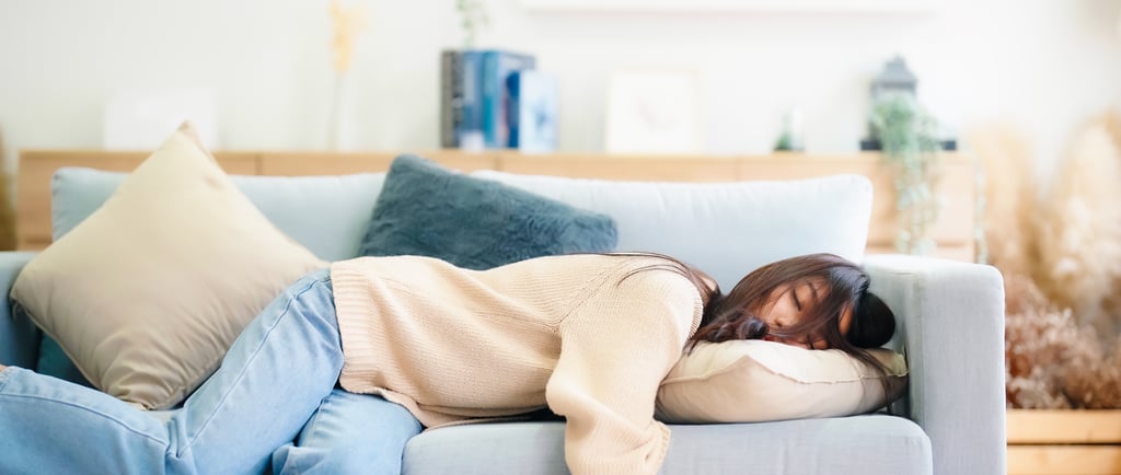 Person napping on a couch with their head on a pillow.