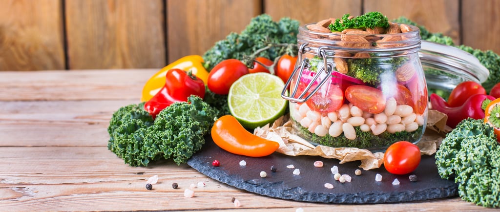 a mason jar of beans and vegetables on a table