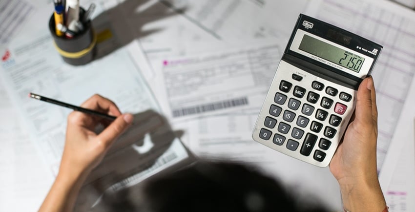 a person holding a calculator and a pen