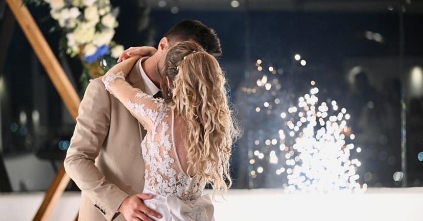 Stage fireworks bursting as the couple shares their first dance in a romantic setting.