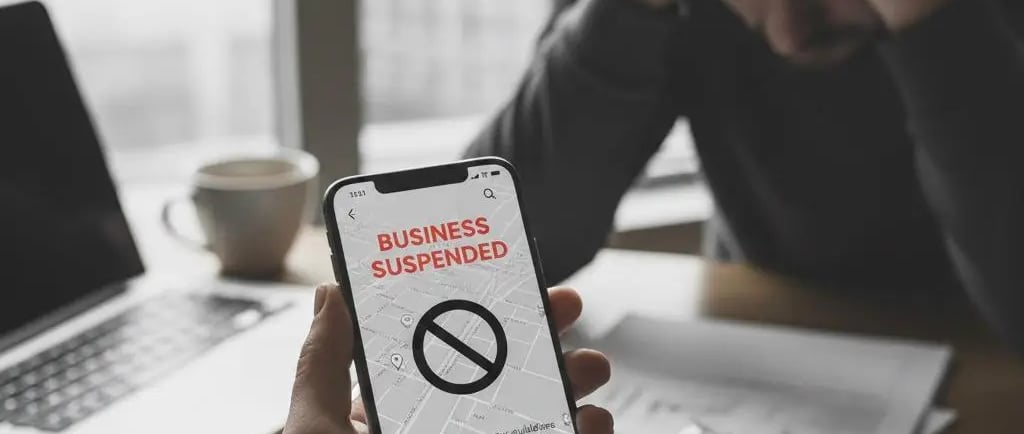 A close-up, ultra-realistic photo of a person holding a smartphone displaying a 'BUSINESS SUSPENDED'