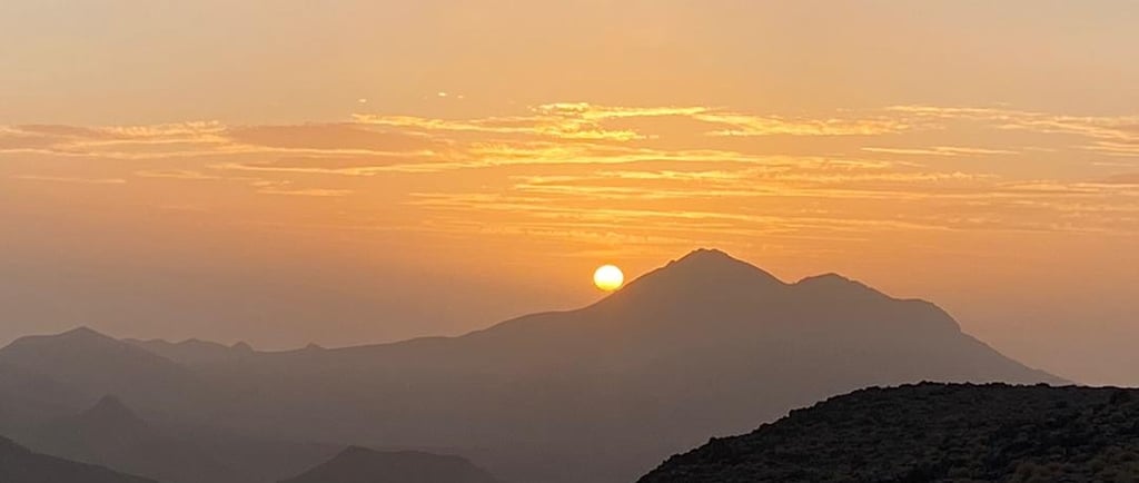 a person standing on a mountain top with a sunset