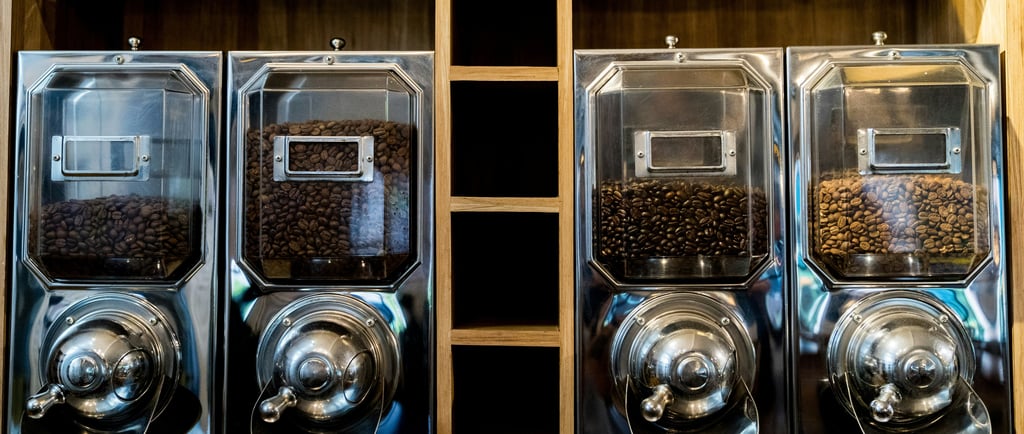 A row of coffee machines sitting on top of a wooden shelf
