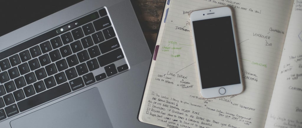 a laptop computer and a notebook with a planner and a cell phone virtual assistant