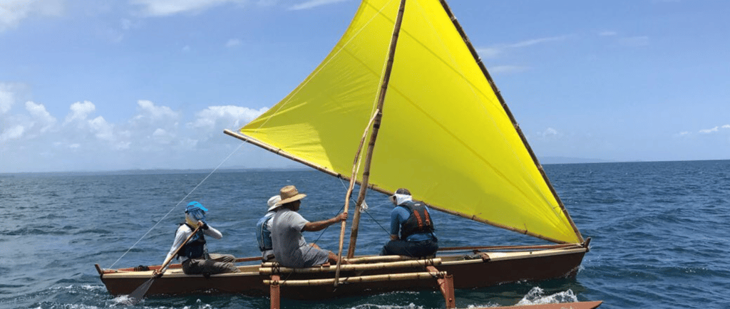 a group of people on a traditional style boat on the water in the Pacific