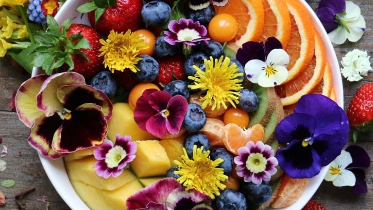 a bowl of fruit and flowers on a table