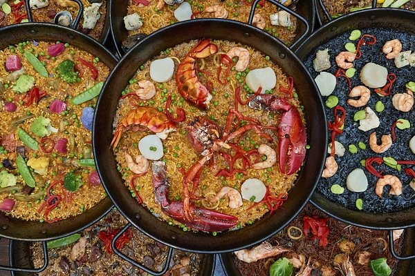 A colorful table filled with traditional Spanish dishes including paella, tortilla Española, and tap