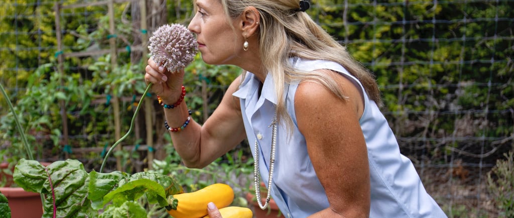 a woman in a blue shirt is holding fresh pick vegetables form the garden 