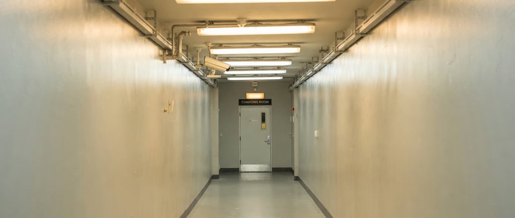 Pasillo de fábrica con cámara de videovigilancia apuntando al acceso de los vestuarios