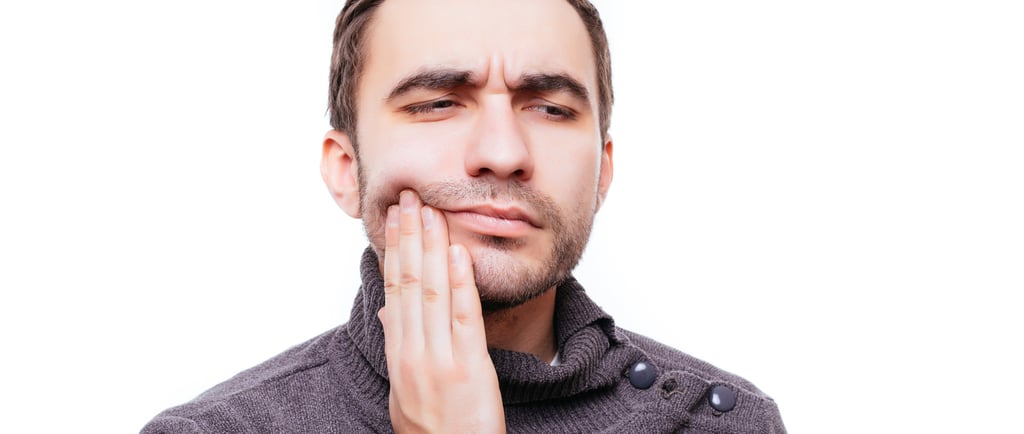 Man holding his cheek in pain due to a severe toothache or dental emergency.