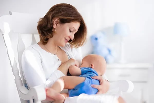 a woman breastfeeding a baby in a rocking chair