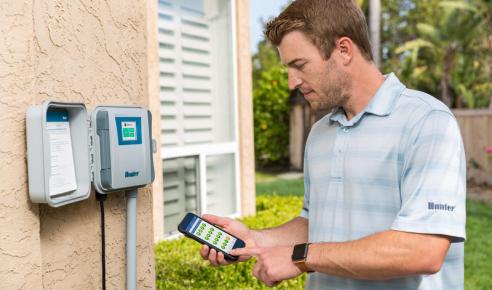 Hunter Hydrawise smart irrigation controller being adjusted with mobile app