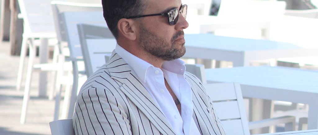 a man in a suit and sunglasses sitting at a table