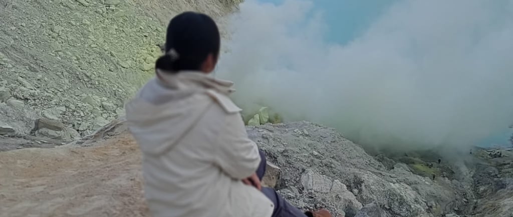 a woman sitting on a rock in the mountains