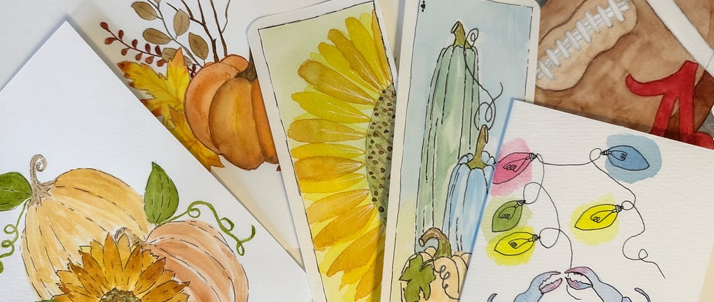 A collection of watercolor paintings laying stacked haphazardly.