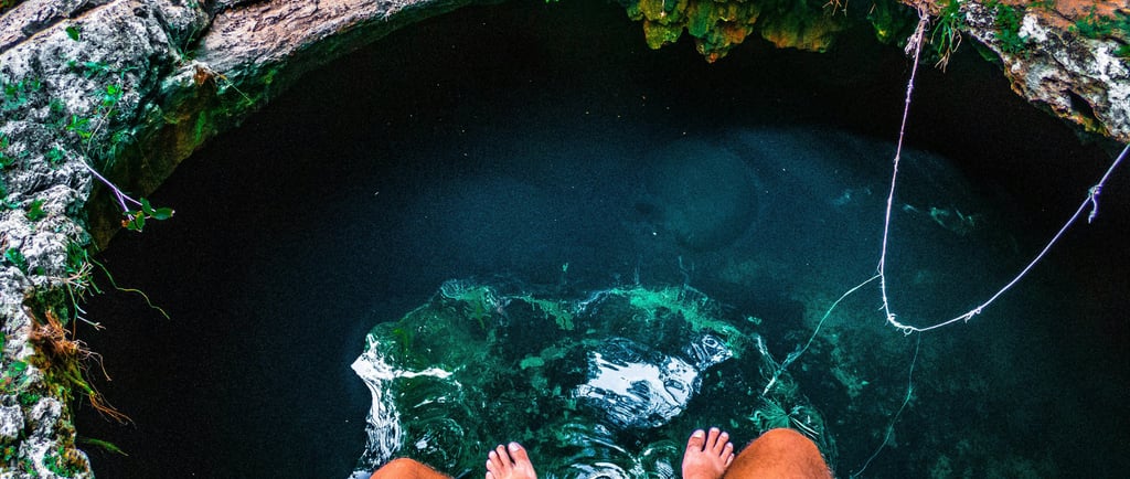 a person sitting on the edge of a Cenotes in Mexico