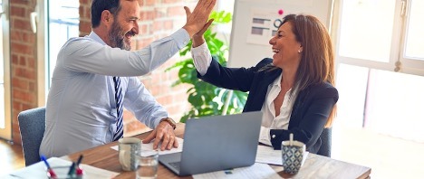 Two cybersecurity professionals celebrating passing their certification exam.