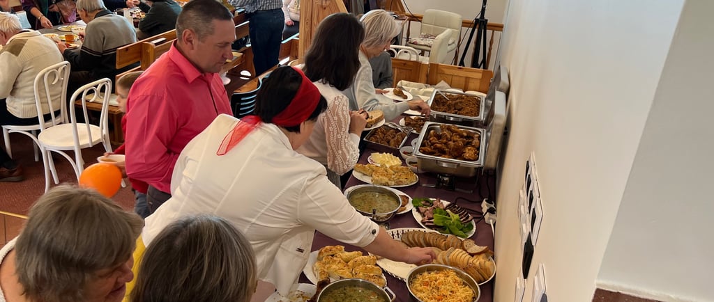 a group of people standing around a table with food