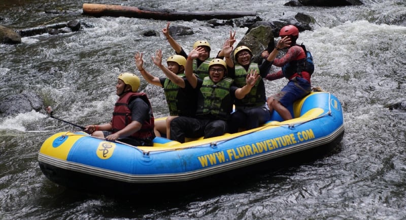 Peserta rafting Pangalengan menyusuri sungai Palayangan dengan pemandangan hutan pinus"