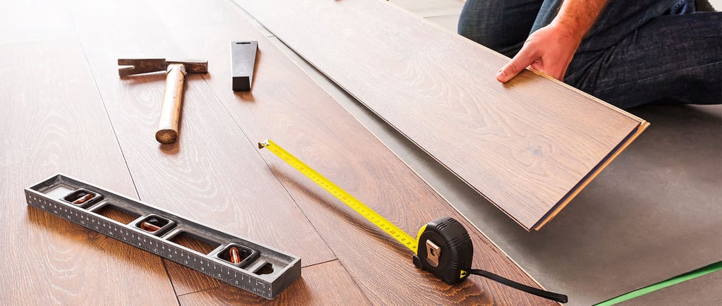 Hardwood flooring installer professionally installing plank flooring.