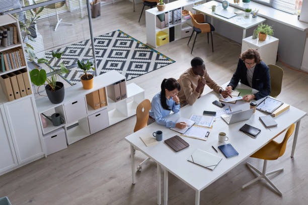 Tres personas sentadas en una mesa y trabajando en la oficina.